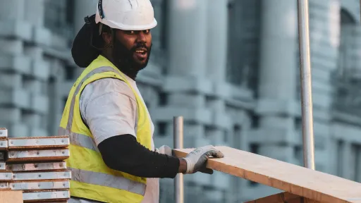 A construction worker picking up a board